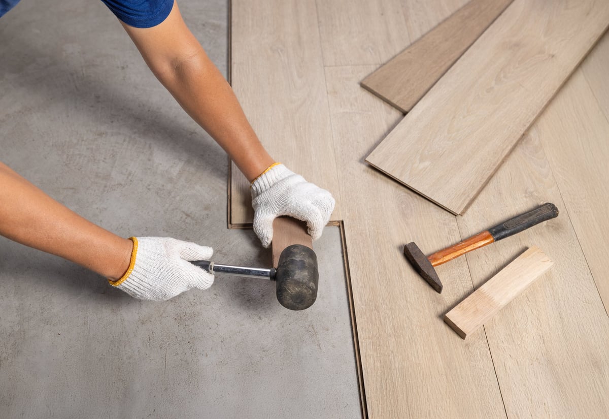 Technician installing new flooring during an apartment unit renovation.