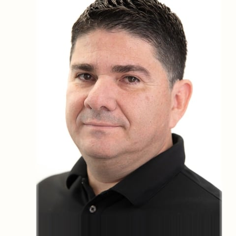Headshot of a middle-aged man with short dark hair wearing a black polo shirt against a white background