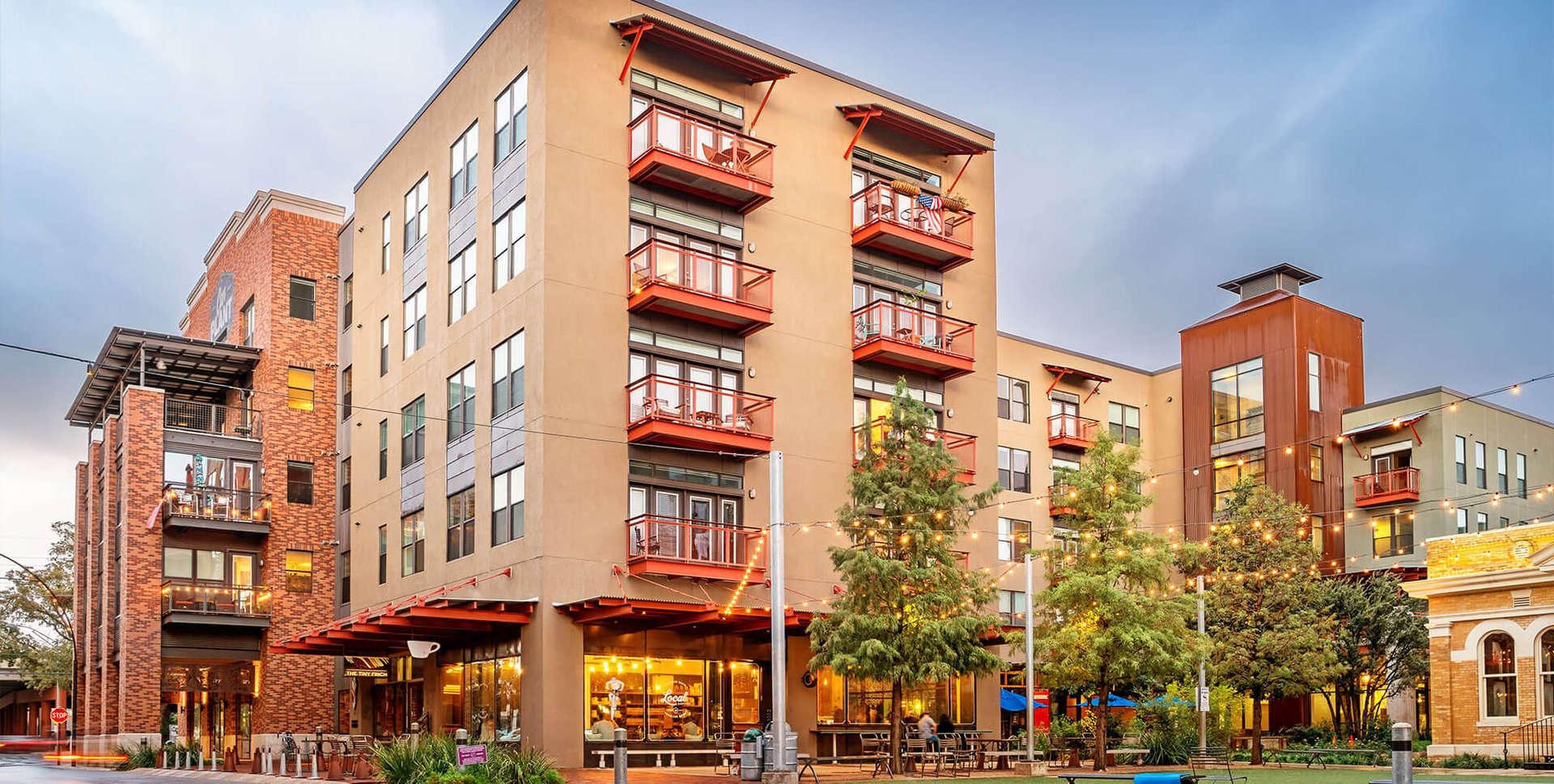 Mixed-use residential and commercial buildings with colorful facades at dusk in an urban neighborhood