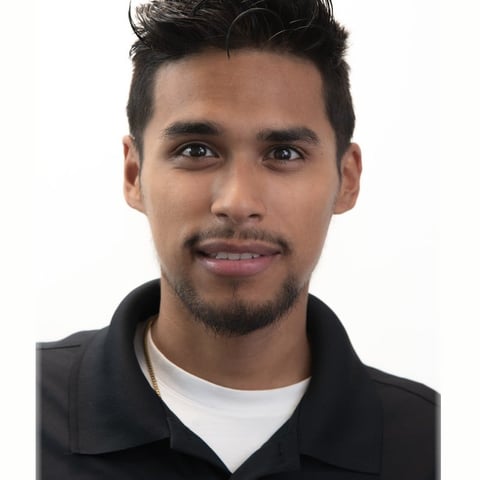 Professional headshot of a man with dark hair and facial hair wearing a black jacket over a white shirt against a white background